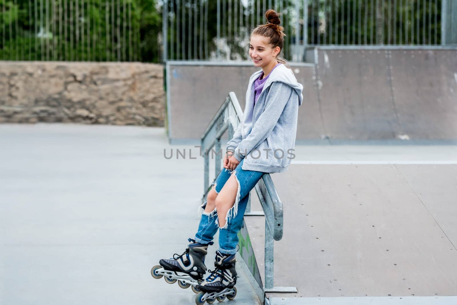 Beautiful girl roller skater riding in city park with ramp. Pretty female teenager rollerskating in casual clothes
