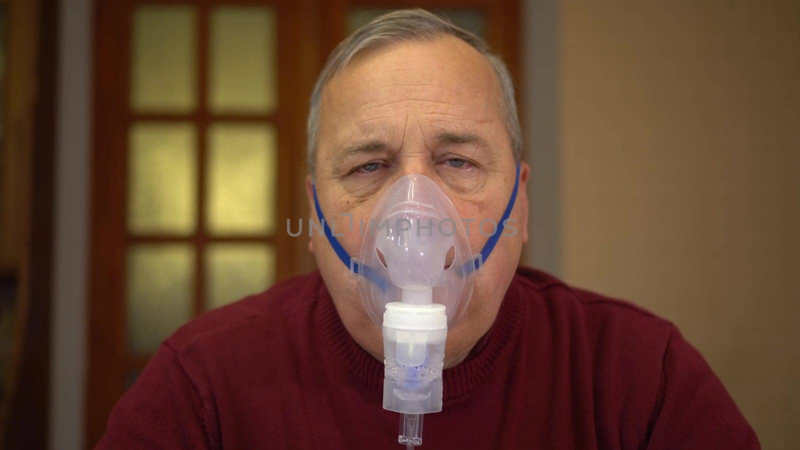 An elderly man inhales through an oxygen mask and looks into the sky. A man does a respiratory procedure at home. 4k