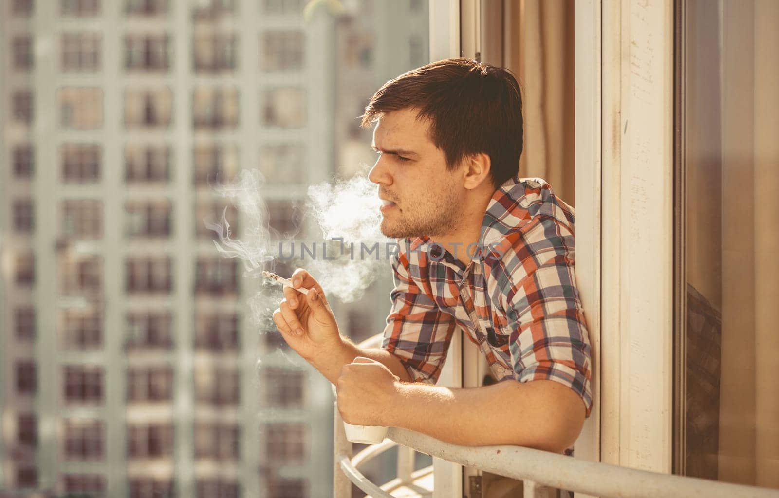 Toned portrait of hipster guy smoking cigarette and drinking coffee