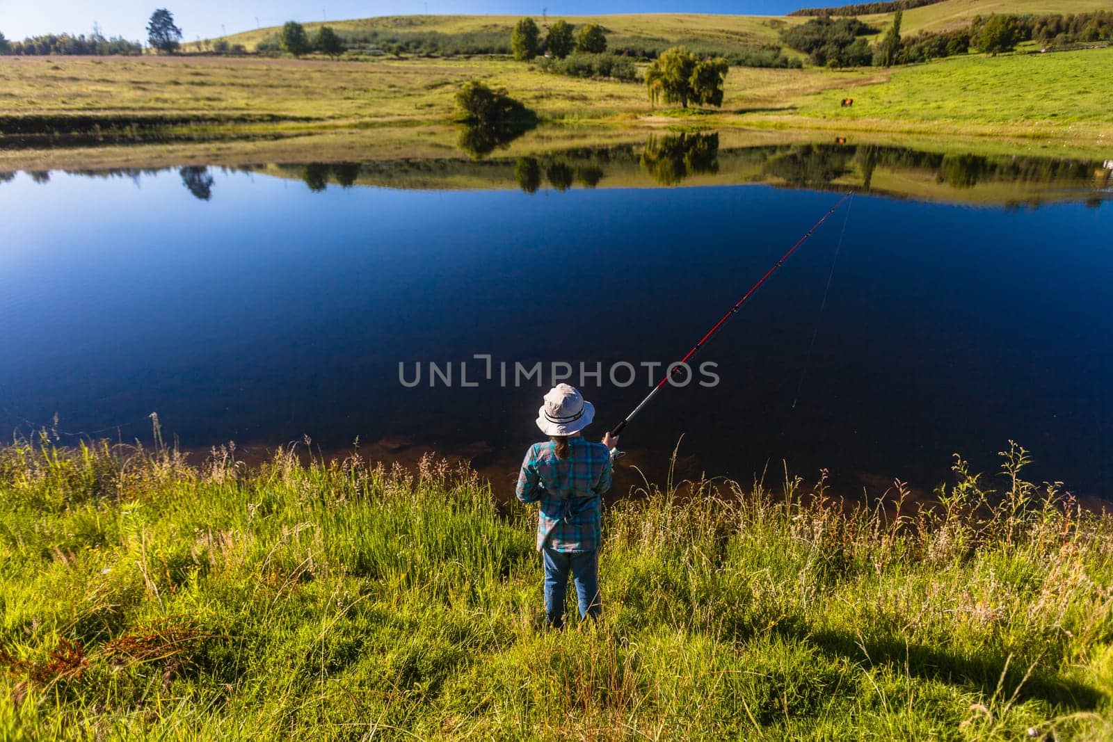 Young girl fishing in mountain dam on a  morning summer day