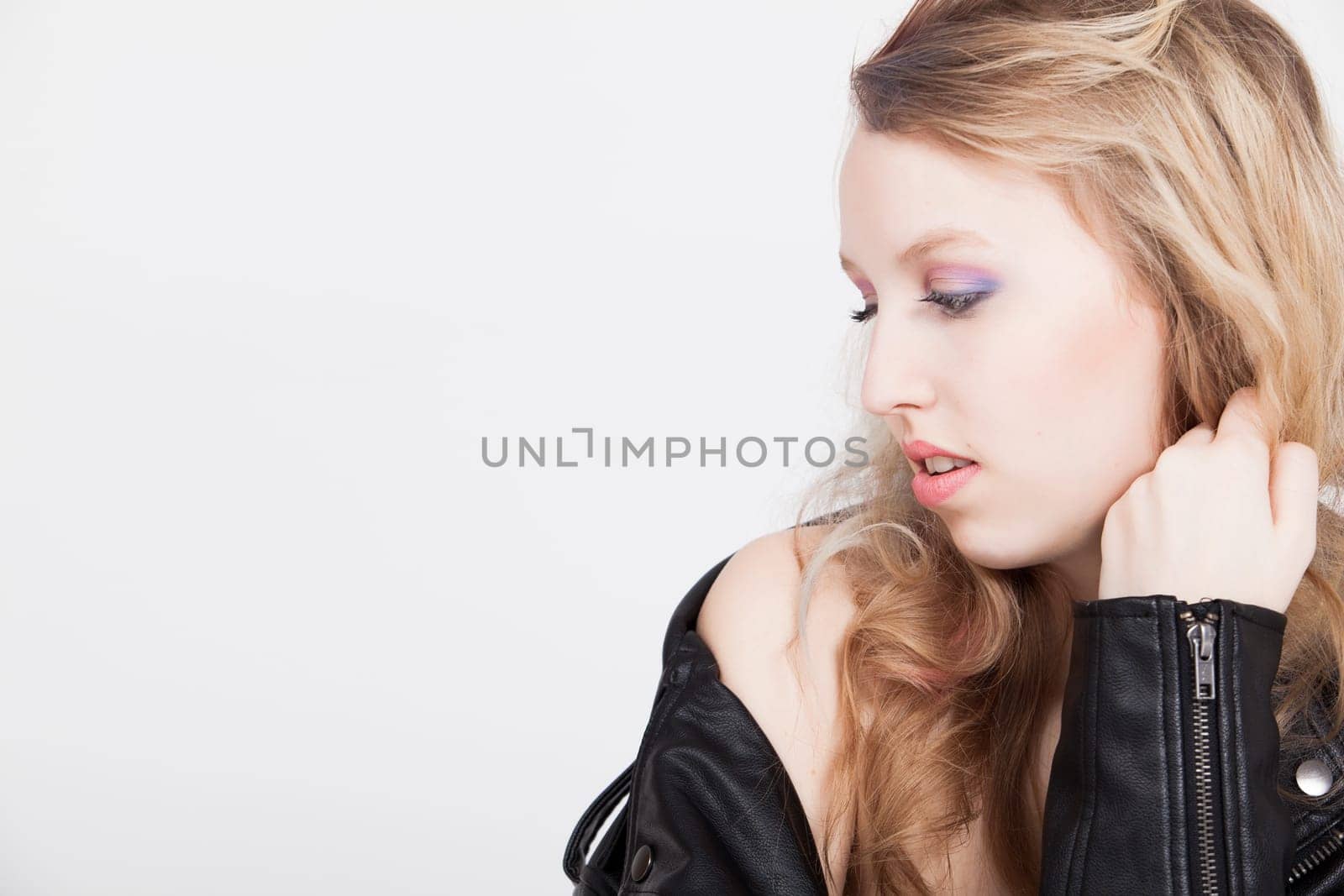Young tough blond teenage girl with leather jacket on a white background