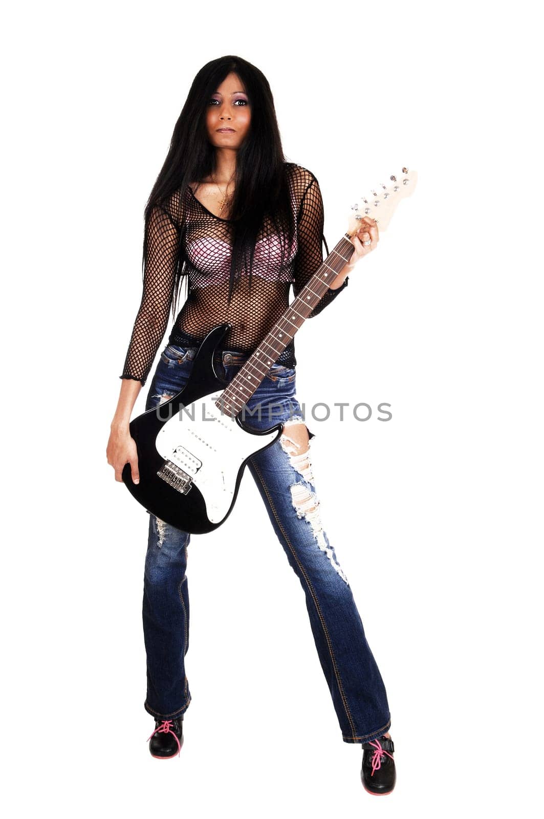 A serious looking Hispanic woman standing isolated for white background .holding her guitar, in ripped jeans..