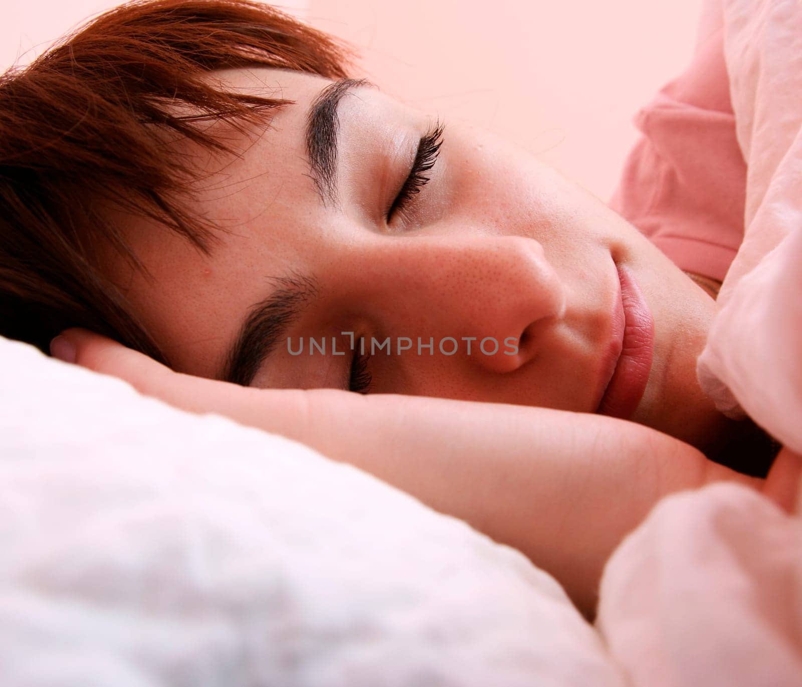 Beautiful young woman sleeping on bed in her bedroom at home in the morning.