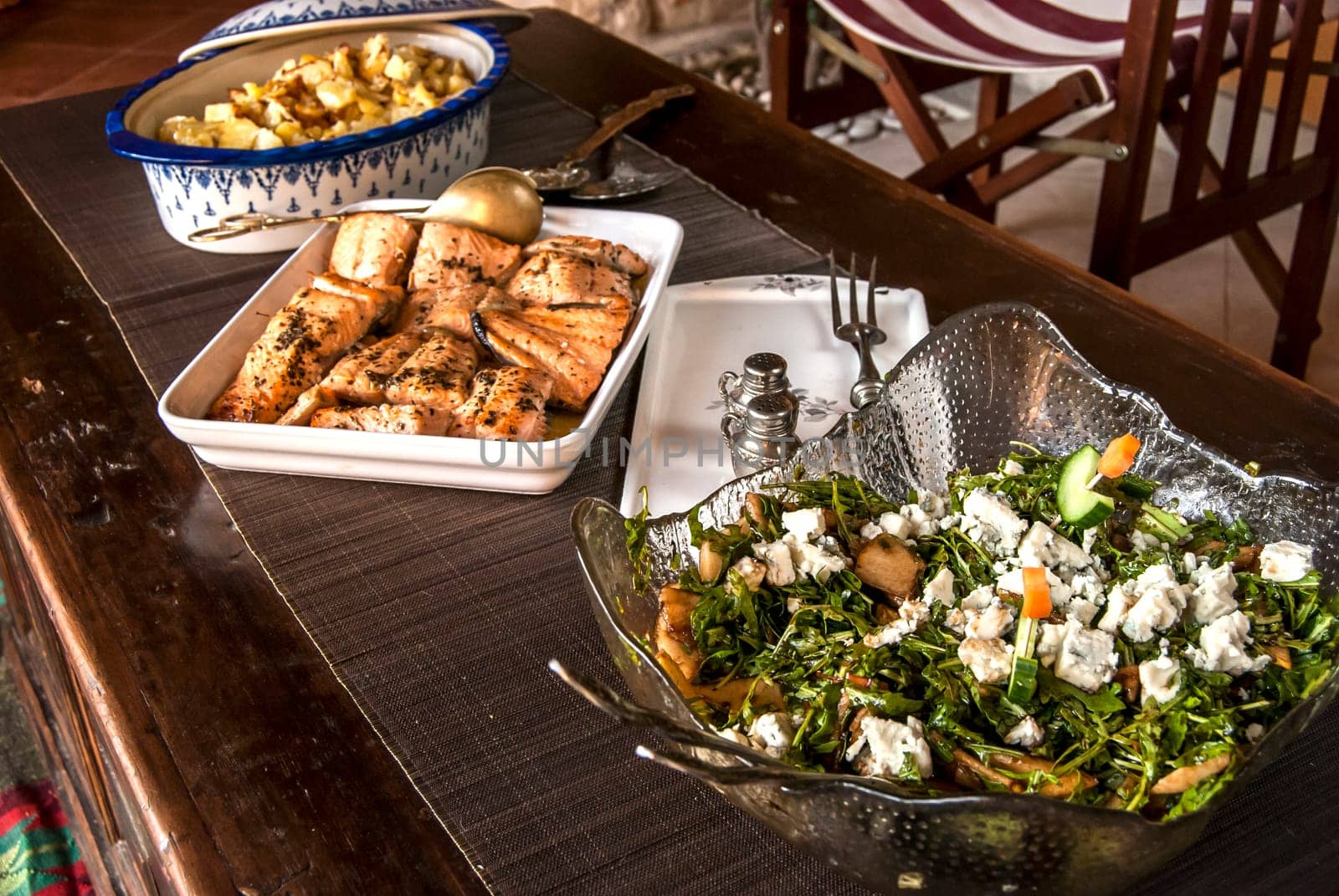 Rustic table with dishes of grilled salmon, salad and sauteed potatoes