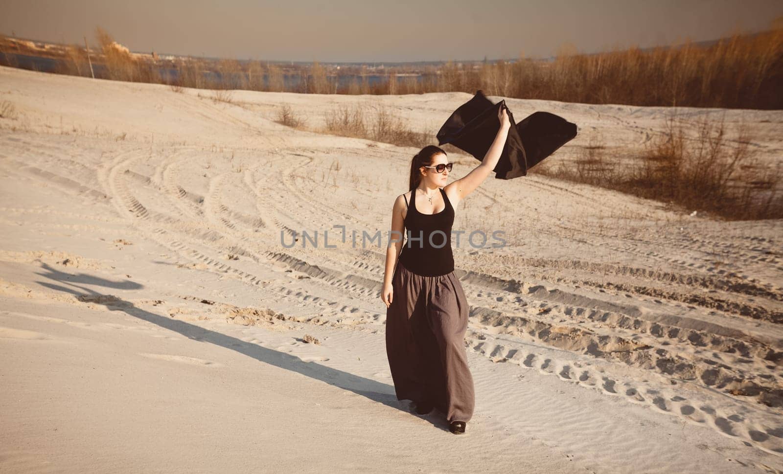 Beautiful slim woman posing at desert with black cloth