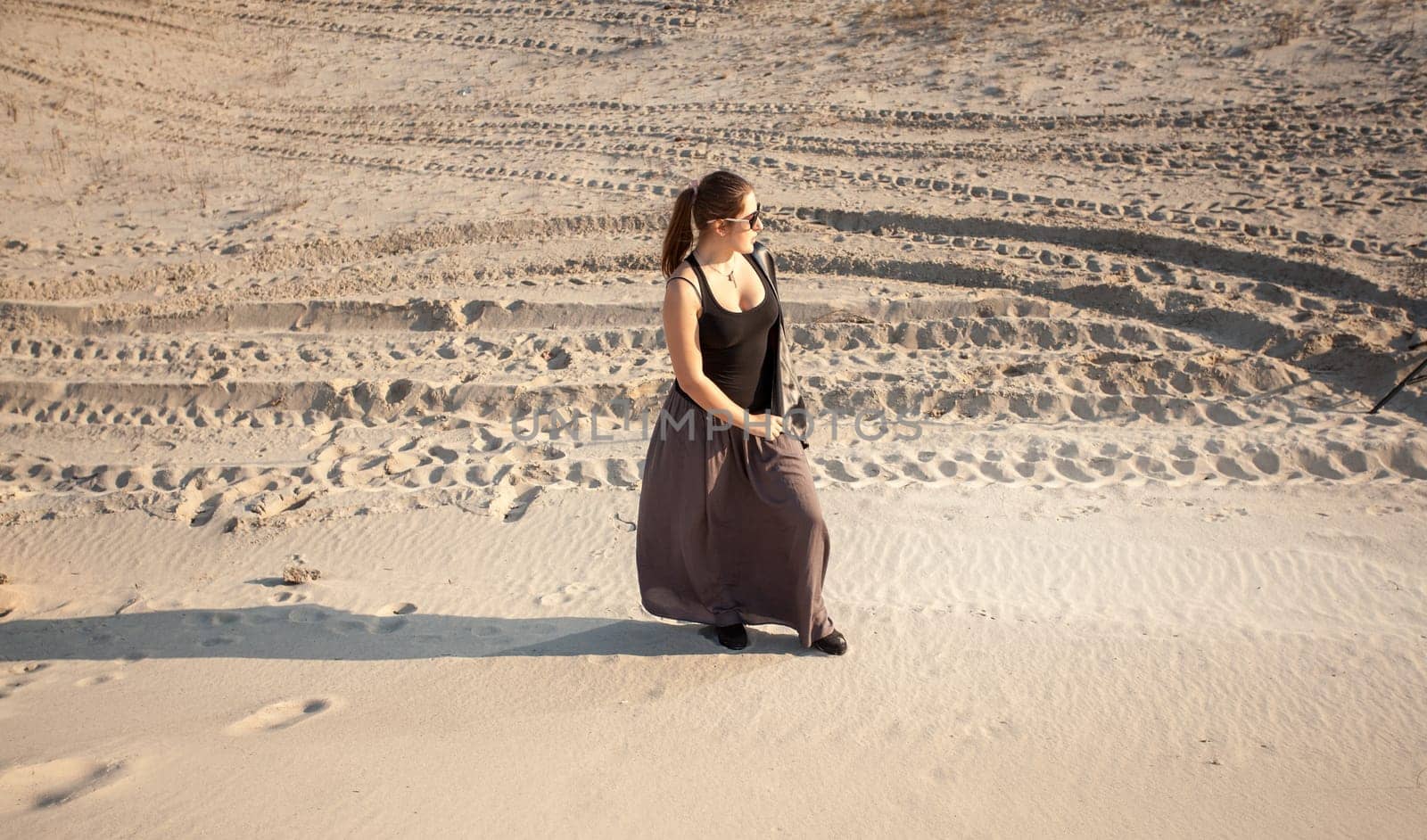 Outdoor photo of lonely woman standing on sand dune