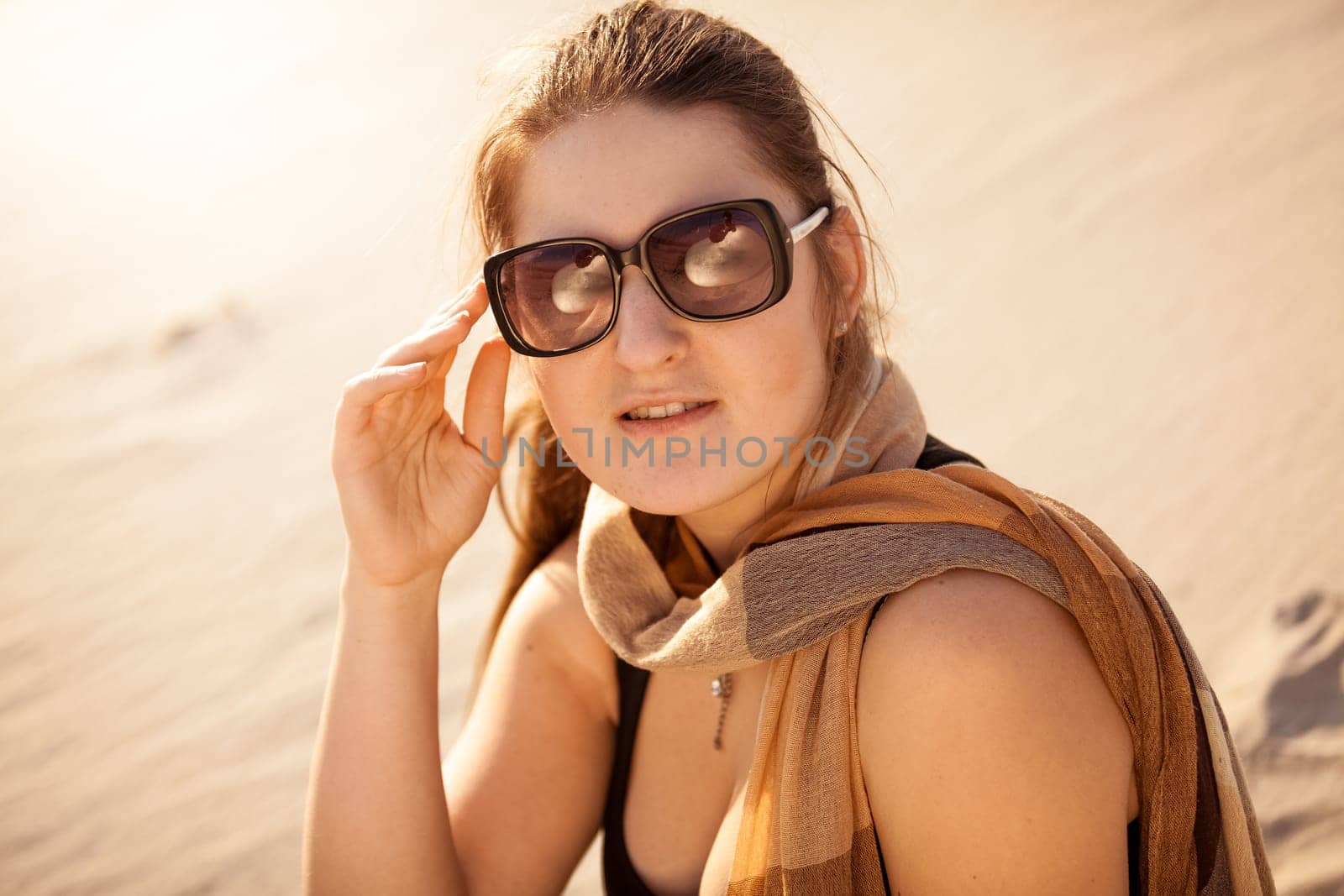 Closeup portrait of brunette woman in sunglasses at sunny day in desert