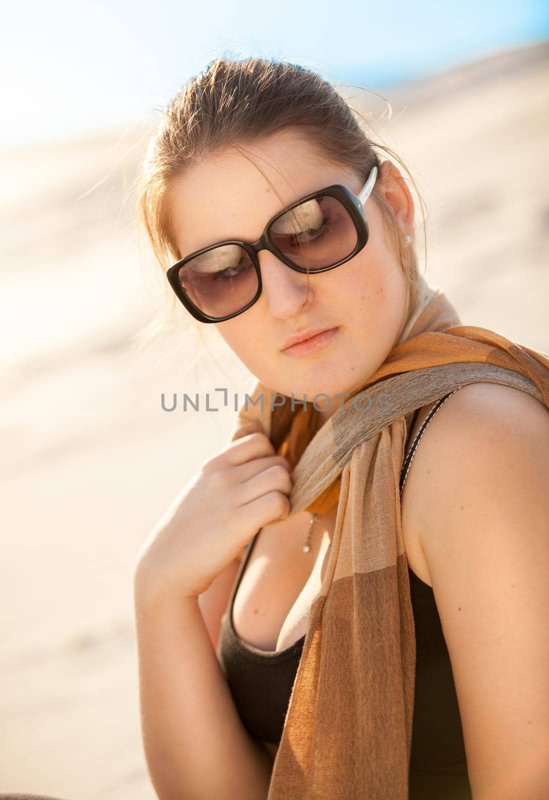 Closeup portrait of brunette woman in sunglasses and scarf at desert