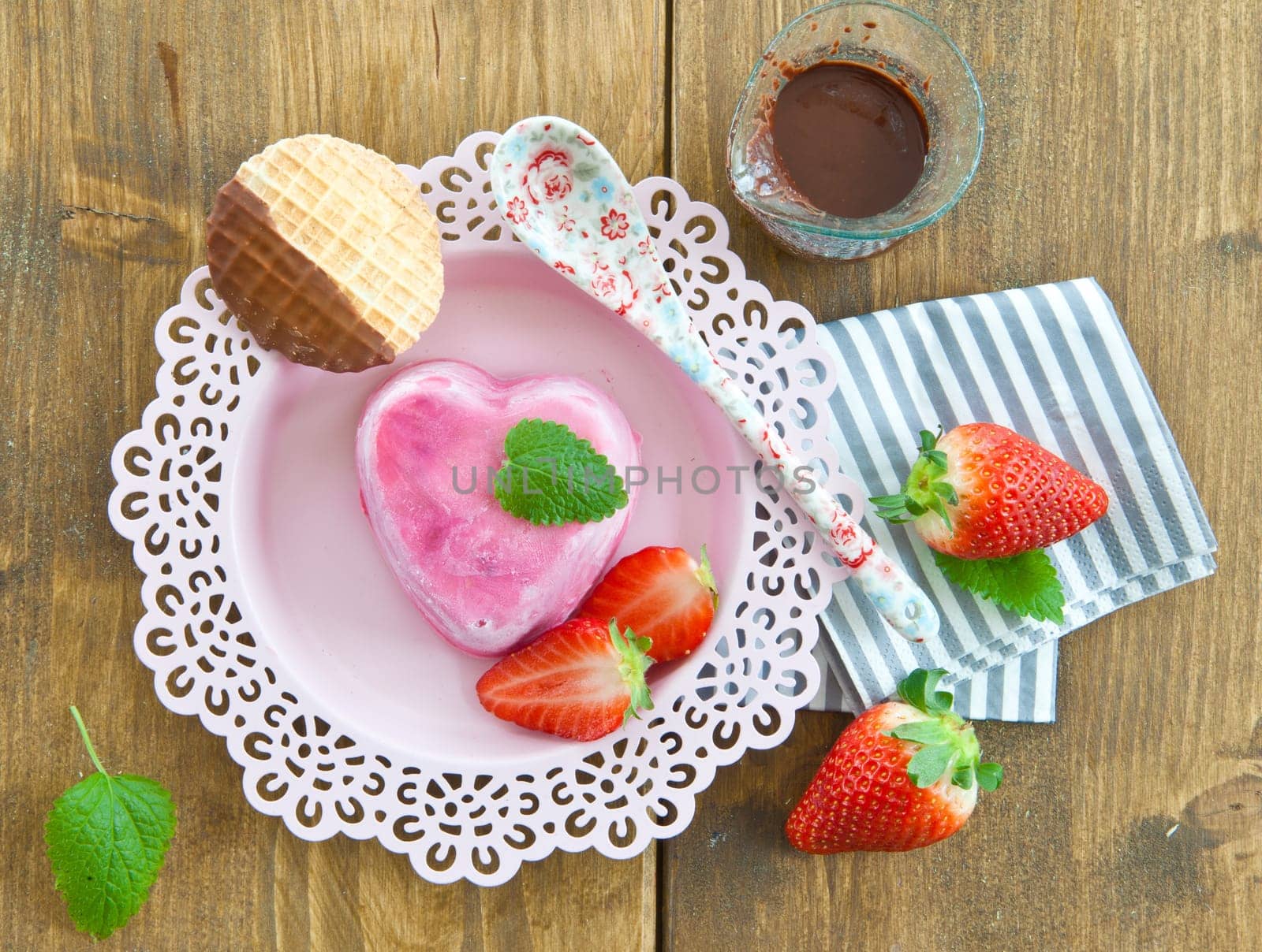 Ice cream in heart shape with fresh strawberries on pink plates