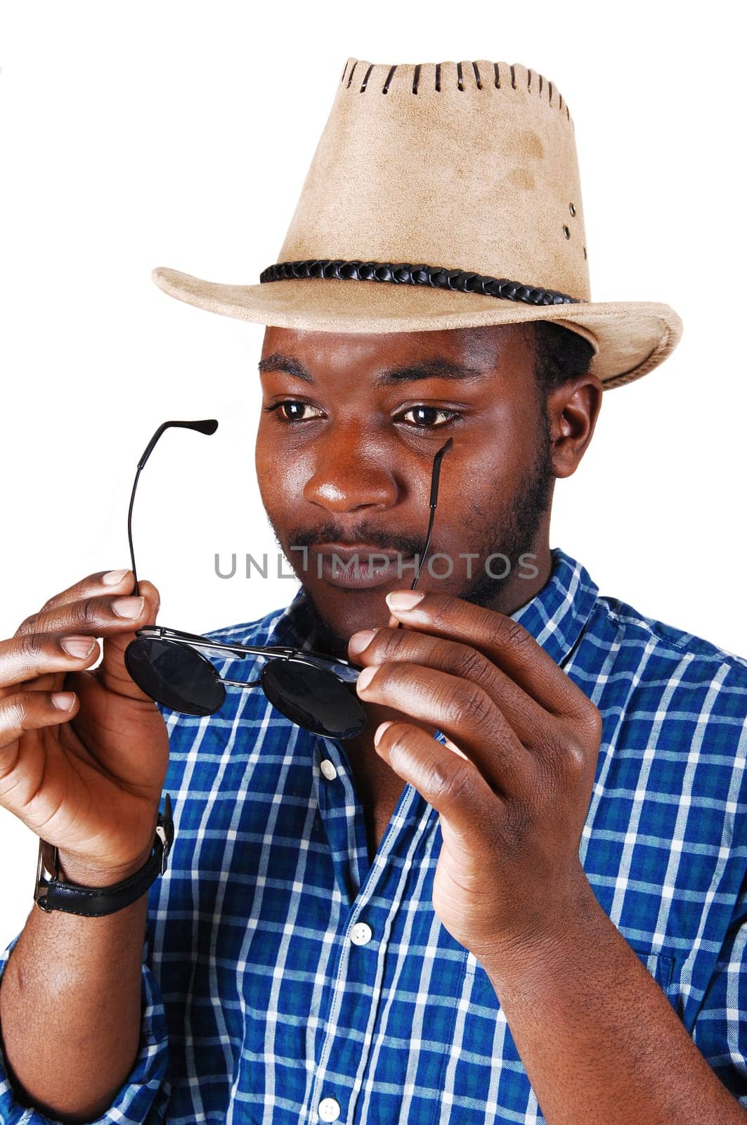 A serious looking black man in a portrait picture with a cowboy hat, holding.his sunglasses, isolated for white background..