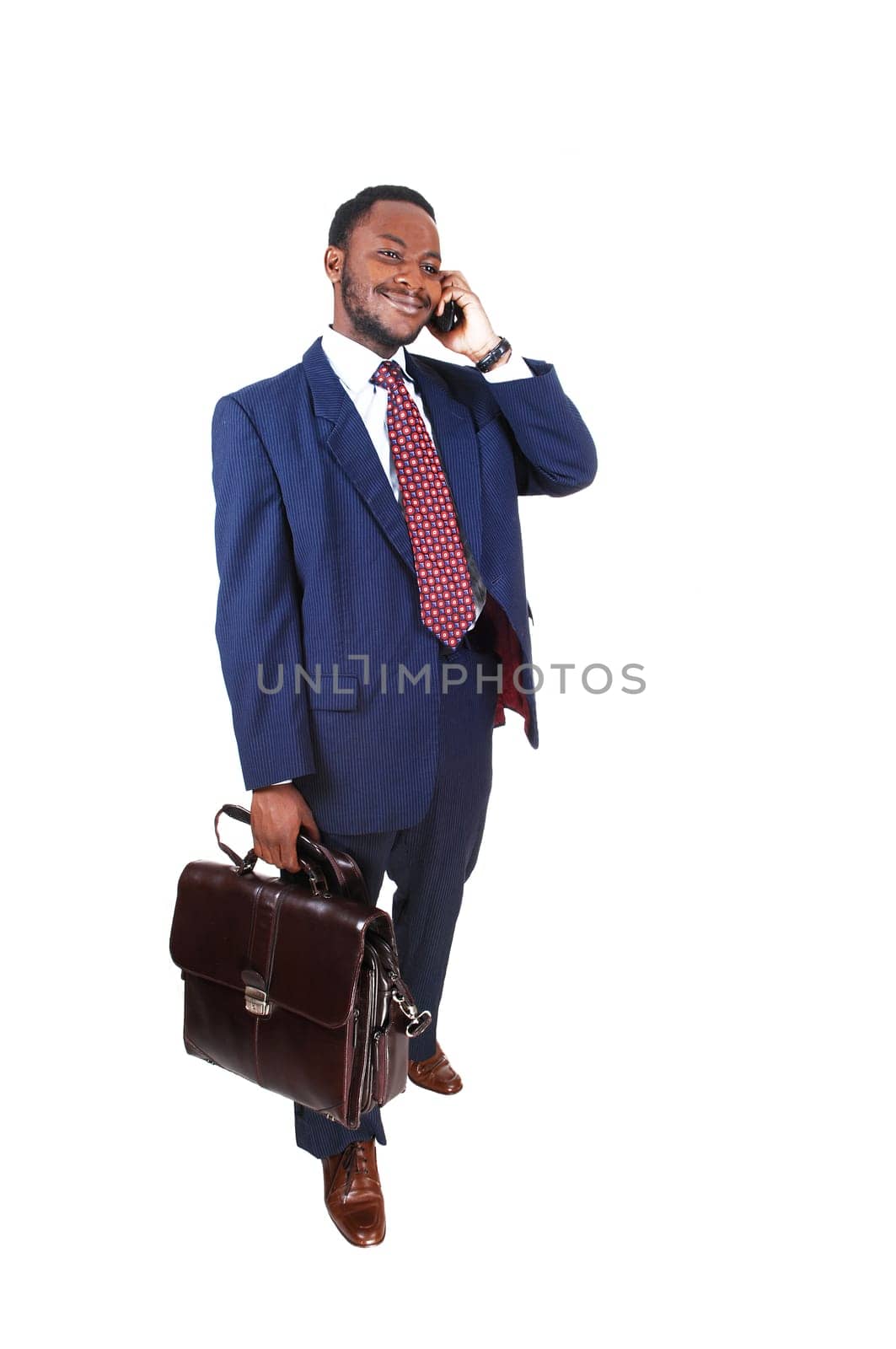 A black businessman standing isolated for white background talking on.the cell phone whit a briefcase in his hand..