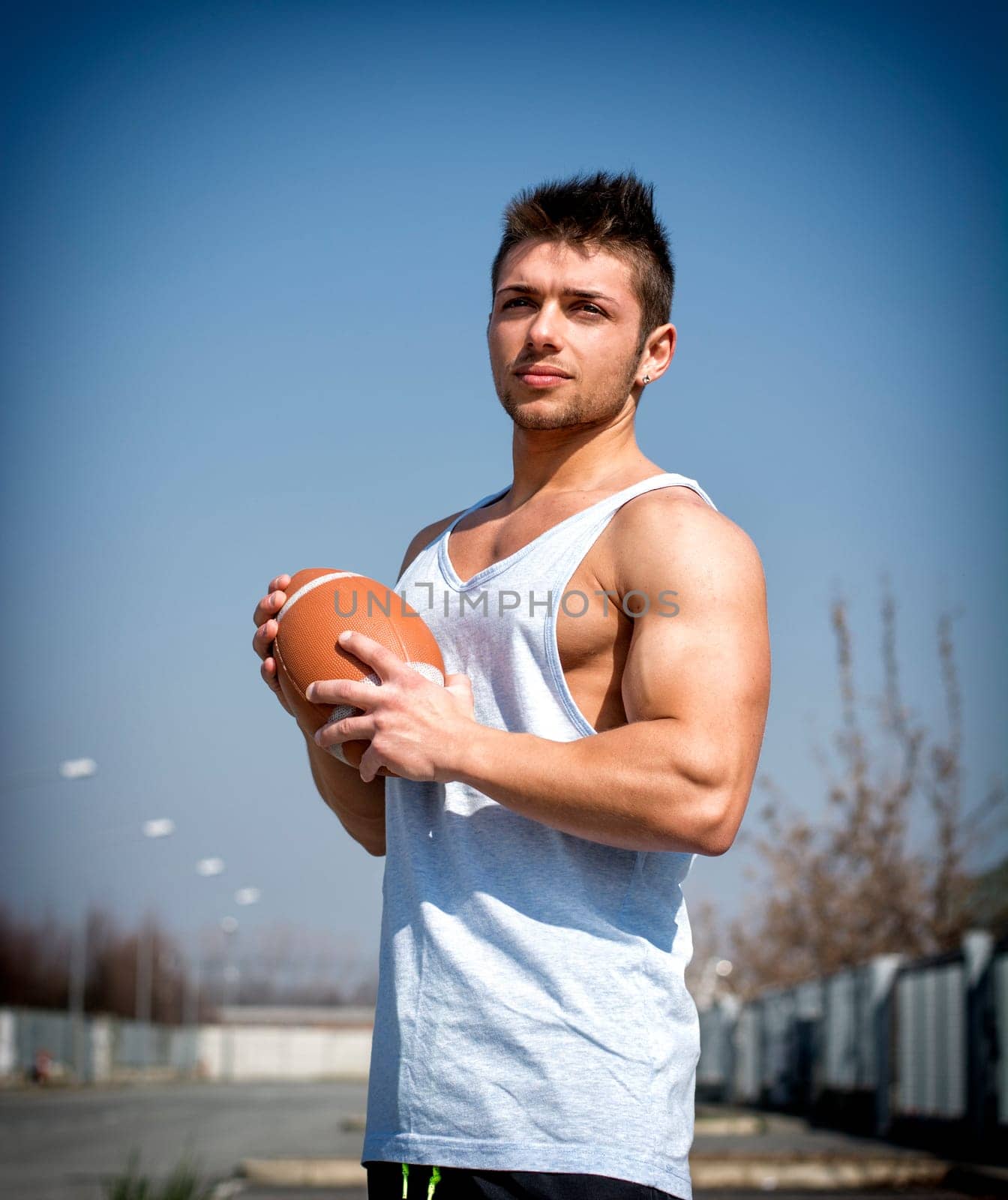 Muscular american football with ball in hand. Outdoors shot