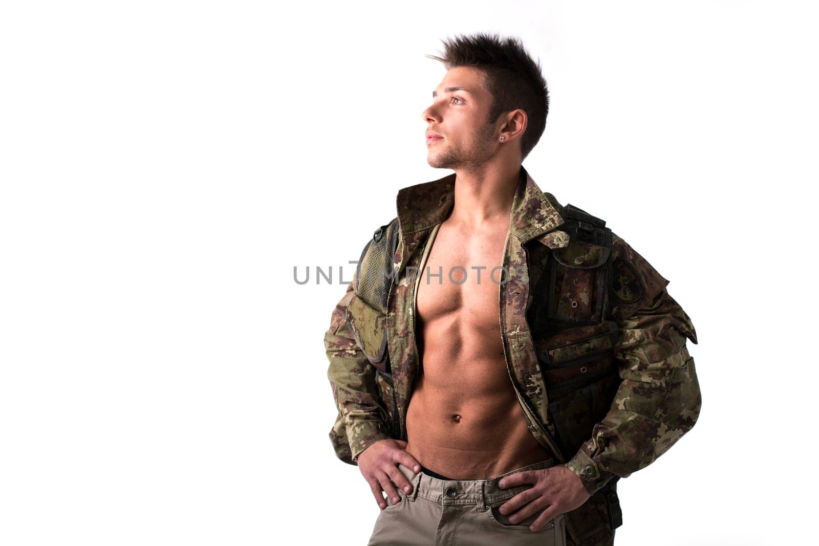 Muscular young man with military jacket on naked torso, isolated on white
