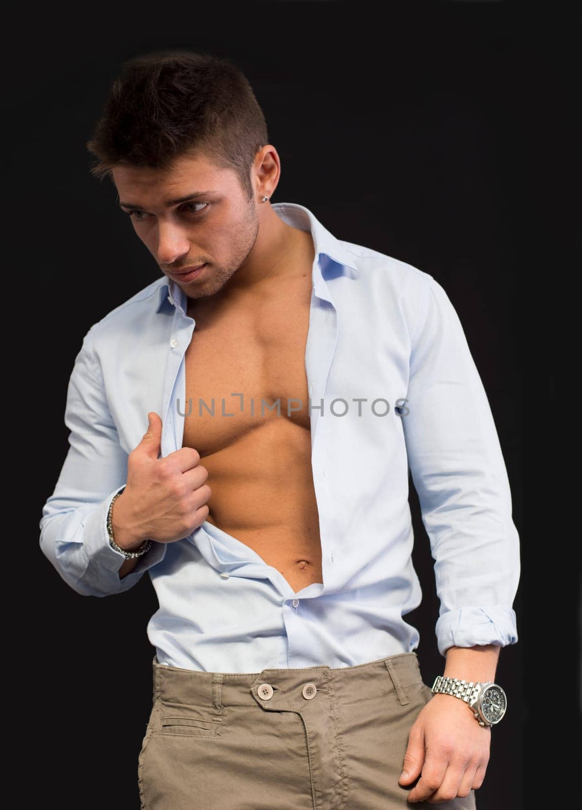 Confident, attractive young man with open shirt on muscular torso, ripped abs and pecs