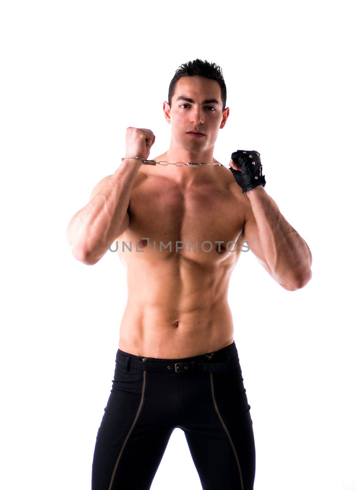 Muscular shirtless young man with handcuffs and studded leather glove, isolated on white