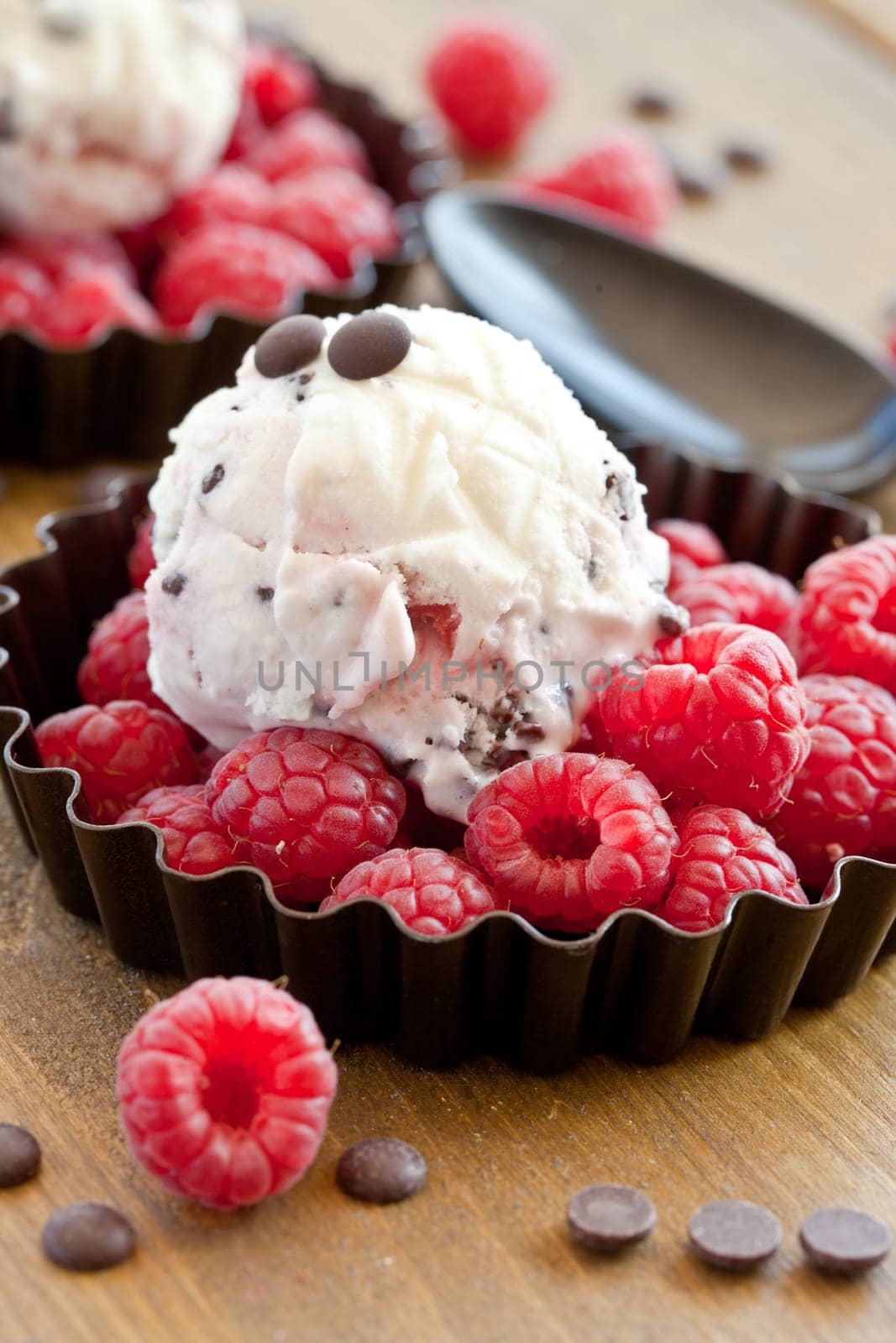 Ice cream with raspberries and chocolate on rustic wood