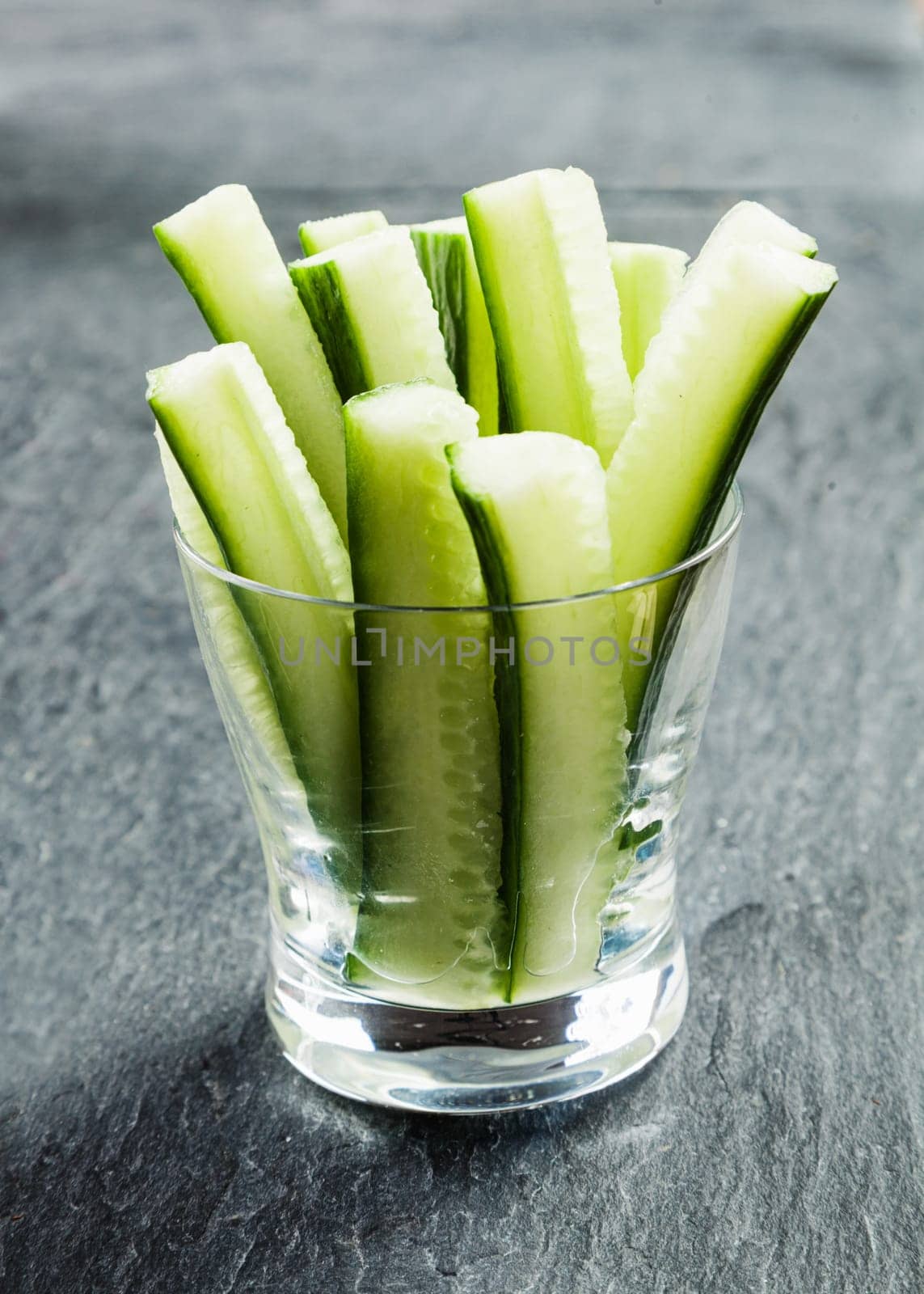Delicious succulent cucumber crudties cut into thin strips or batons and served in a glass container on a buffet as appetizers to dip in a savory sauce