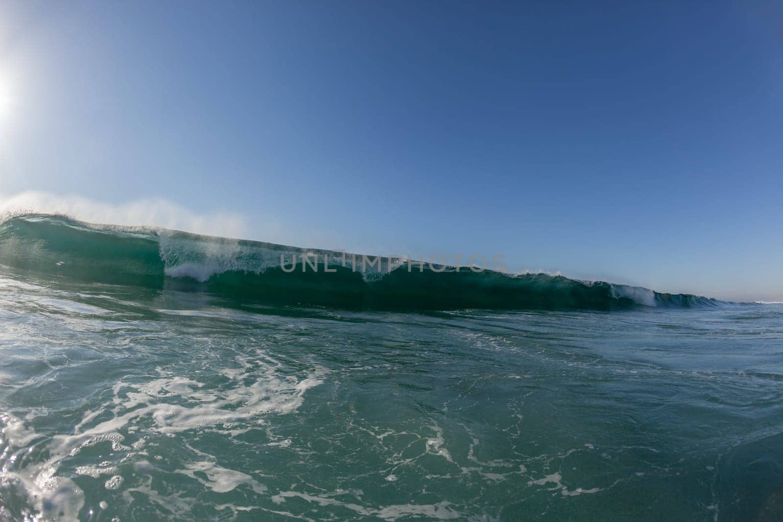 Ocean wave crashing water power energy on shallow reefs nearby beach coastline