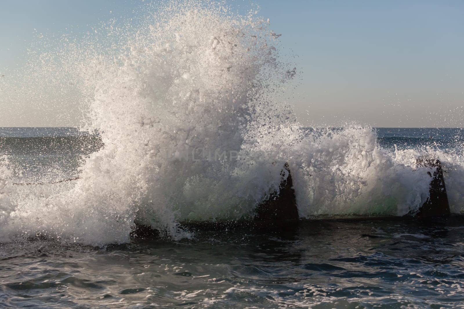 Ocean wave crashing white water spray against tidal pool coastline