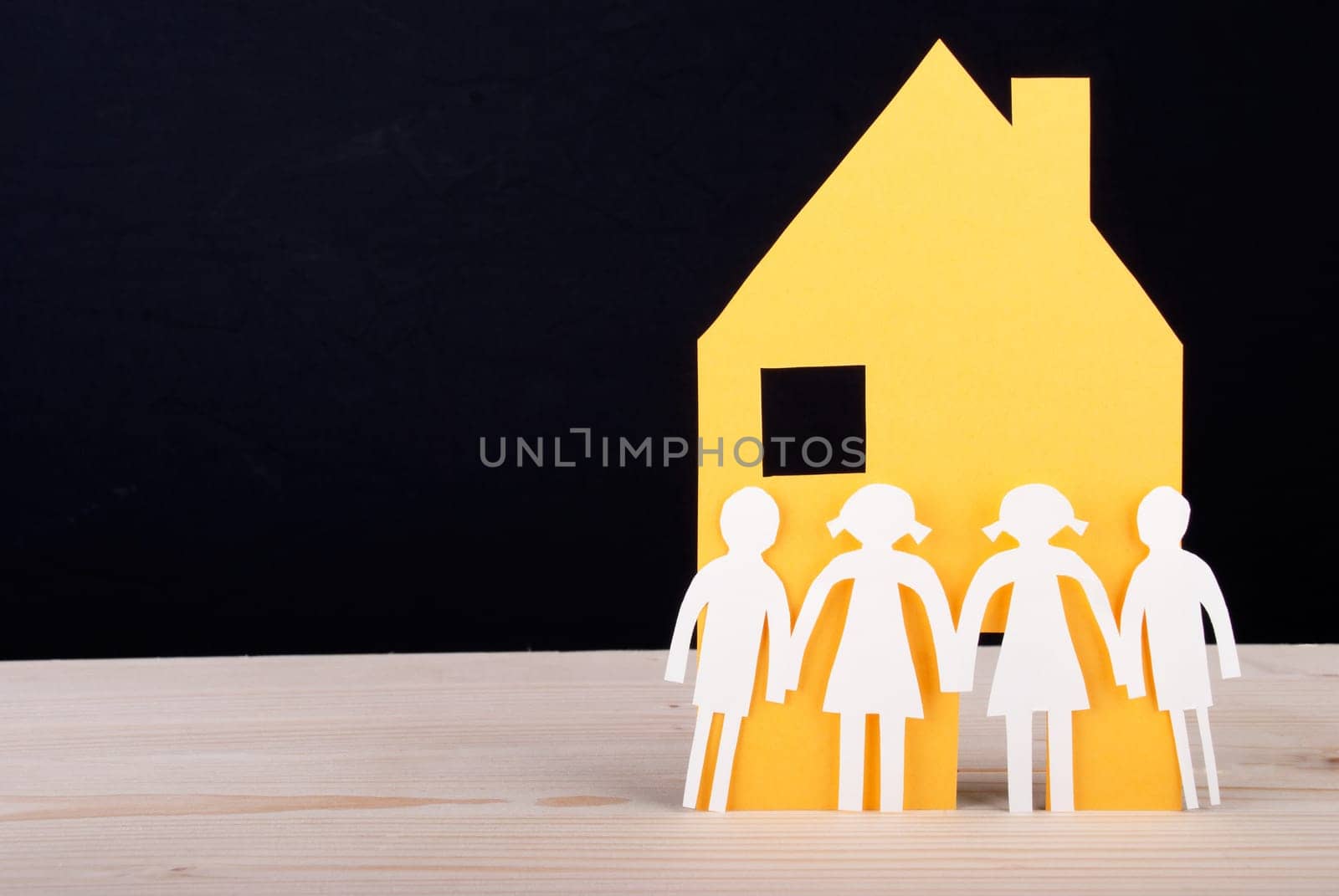 White Paper Chain Children in front of a Yellow Paper House, Black Background