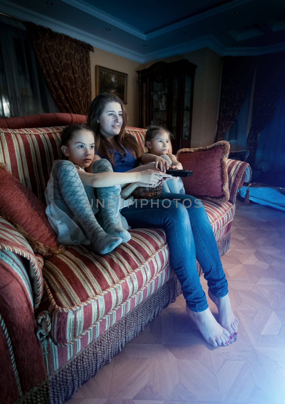 Young mother with two daughters watching horror movie at night