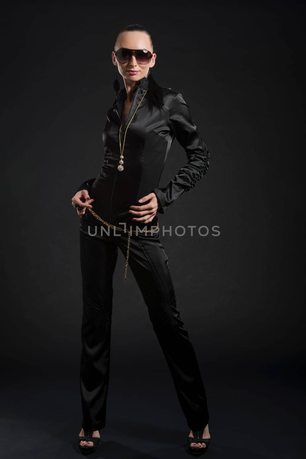 Full length shot of beautiful Caucasian woman wearing black bodysuit against black background