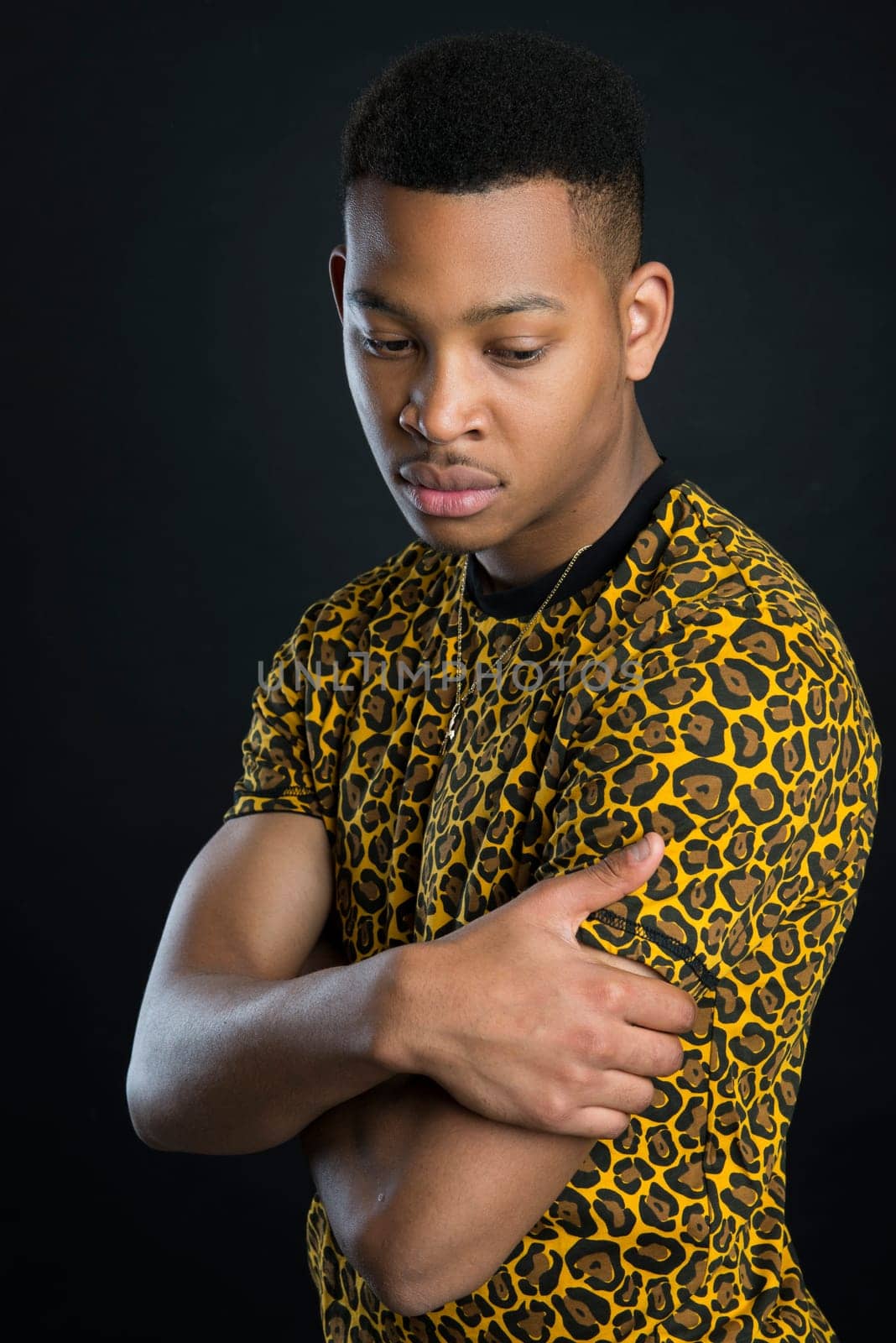 Portrait of handsome dark skinned male model wearing panther pattern t-shirt against black background