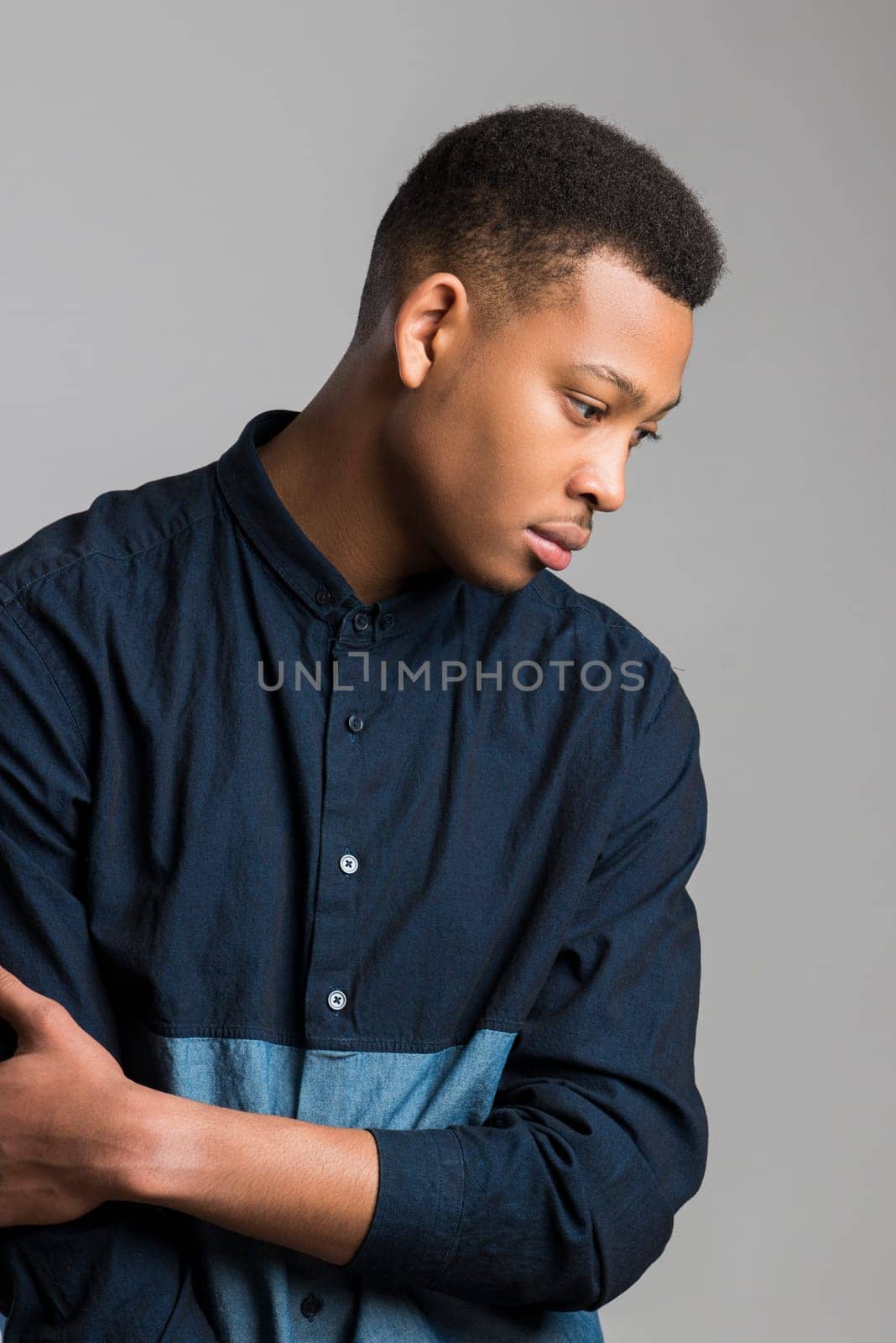 Profile portrait of handsome dark skinned male model wearing casual clothes against white background