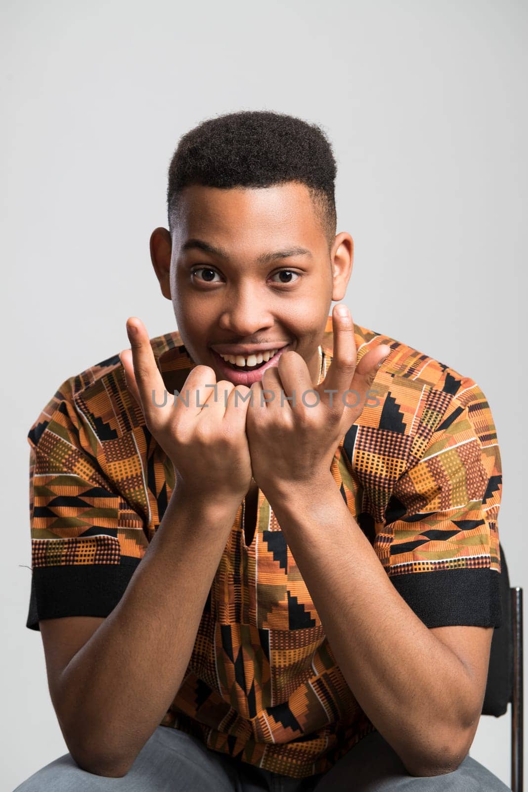 Portrait of handsome dark skinned male model smiling and wearing traditionally African clothes against white background