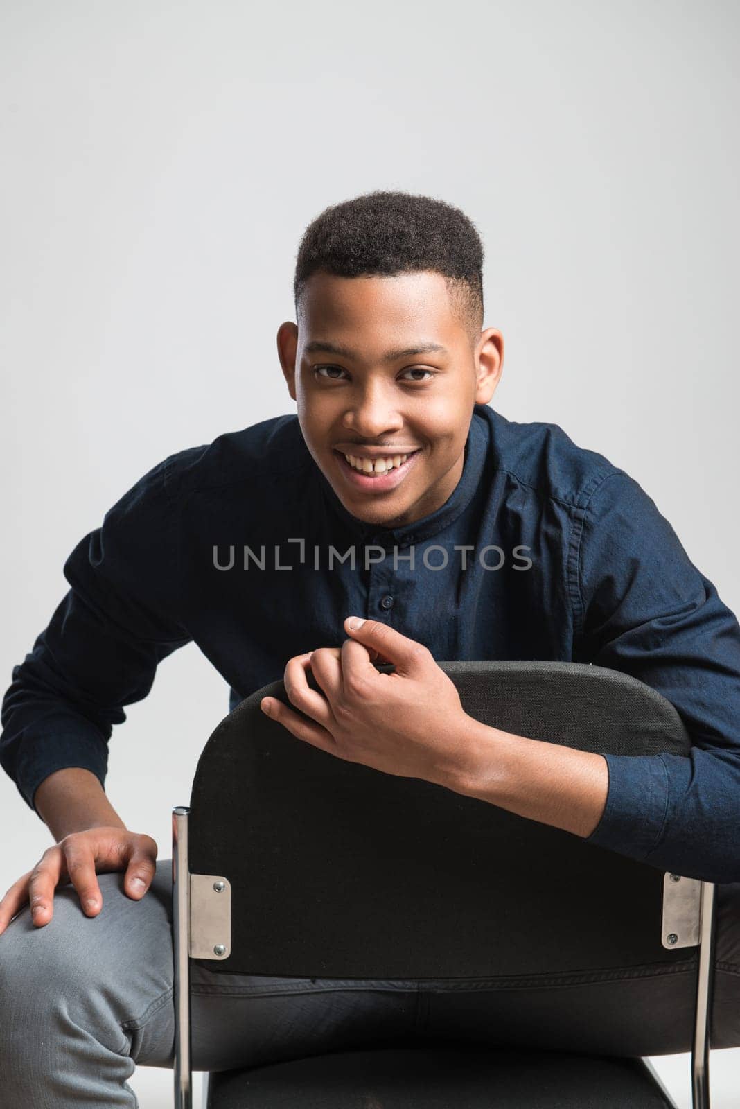 Portrait of handsome dark skinned male model smiling and wearing casual clothes against white background