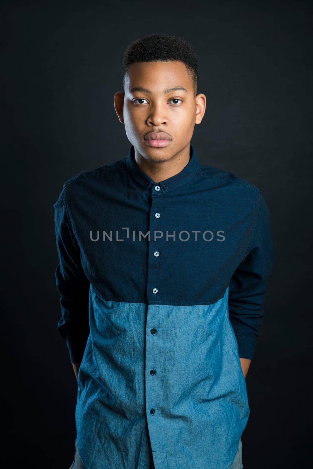 Portrait of handsome dark skinned male model wearing casual clothes against black background