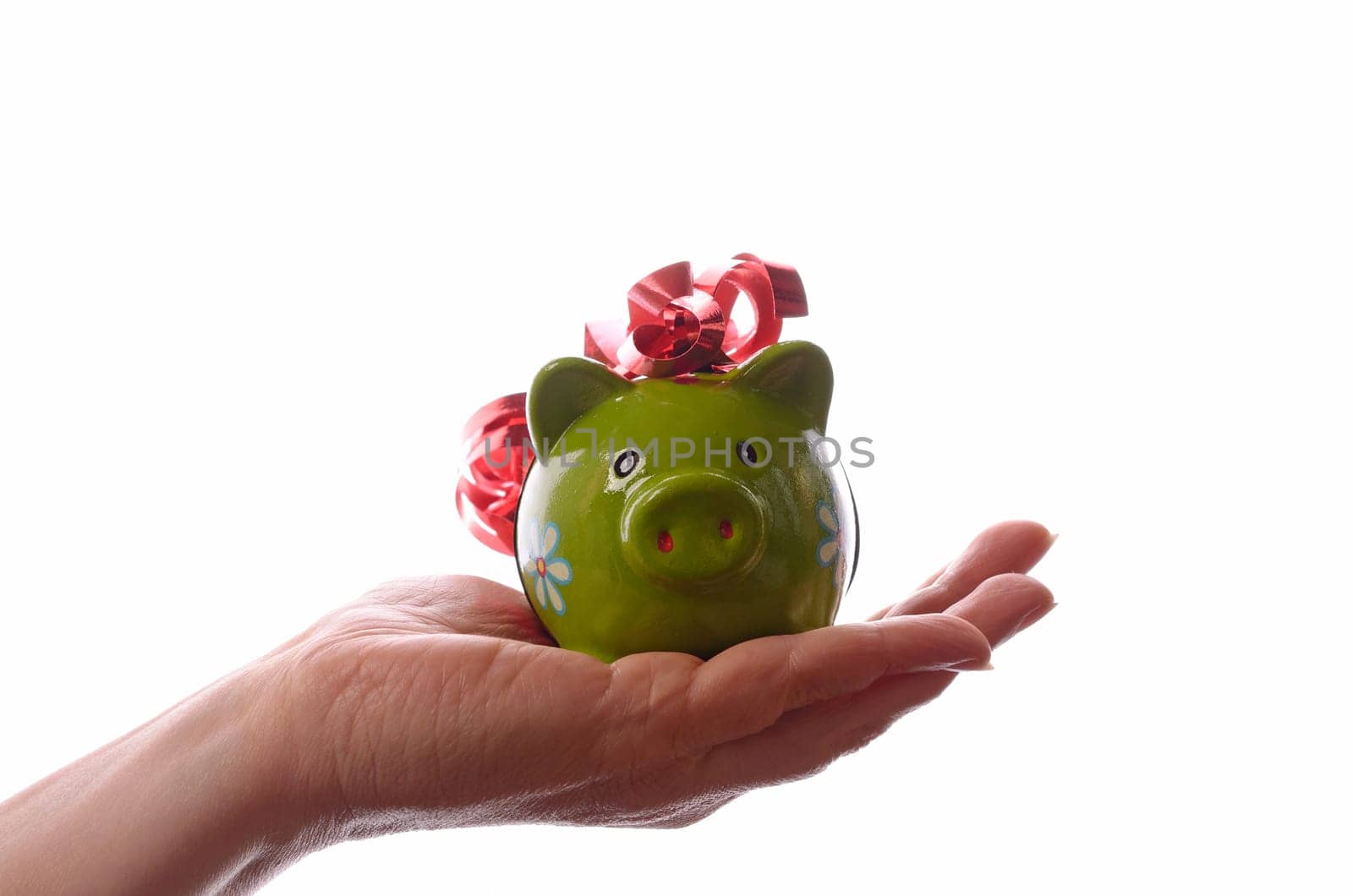 Female hand holding a green piggy bank with a red bow