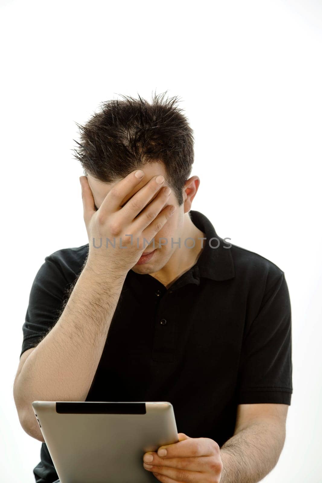 Portrait of a unhappy young man with tablet pc against white background