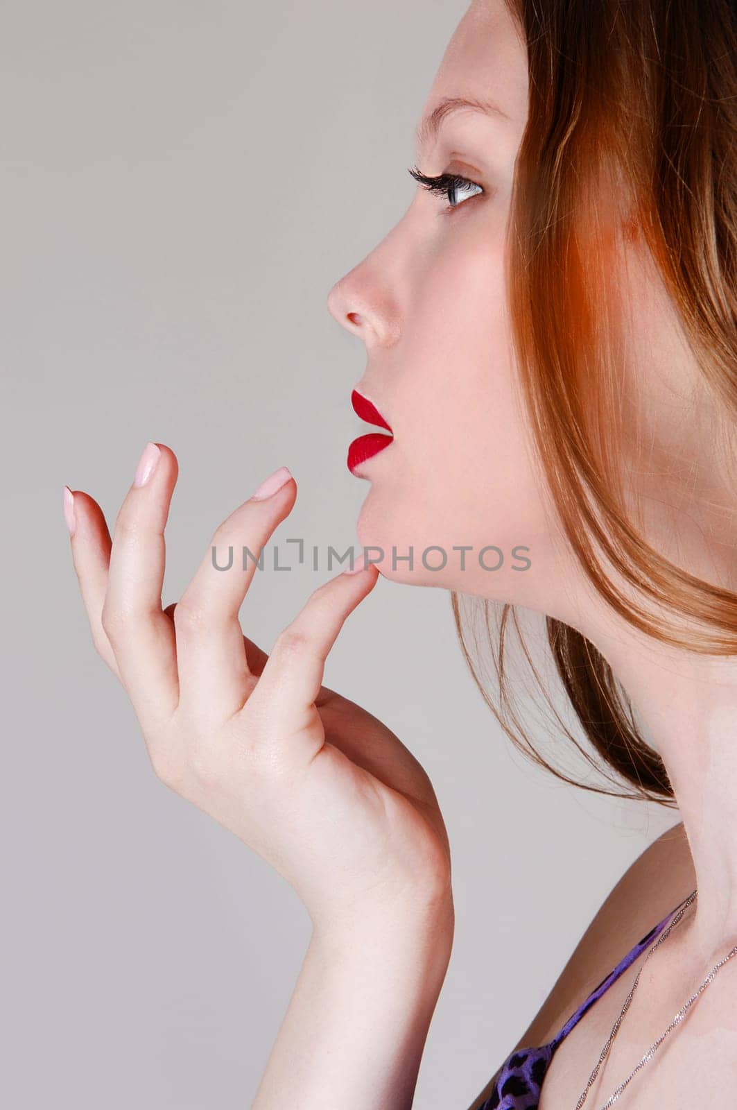 A closeup portrait picture of a halve face of a young woman, holding her.hand on her chin, isolated for light grey background..