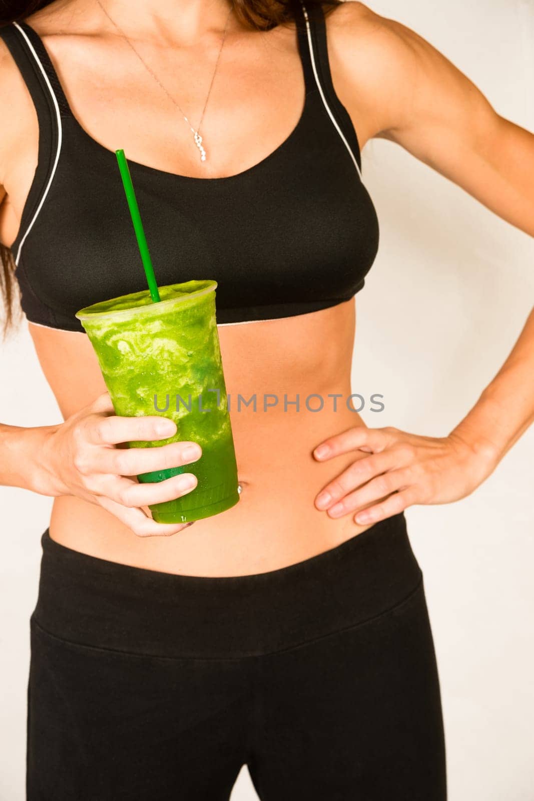 Woman holds Green Fruit Smoothie Waist Level Showing Healthy Slender Body