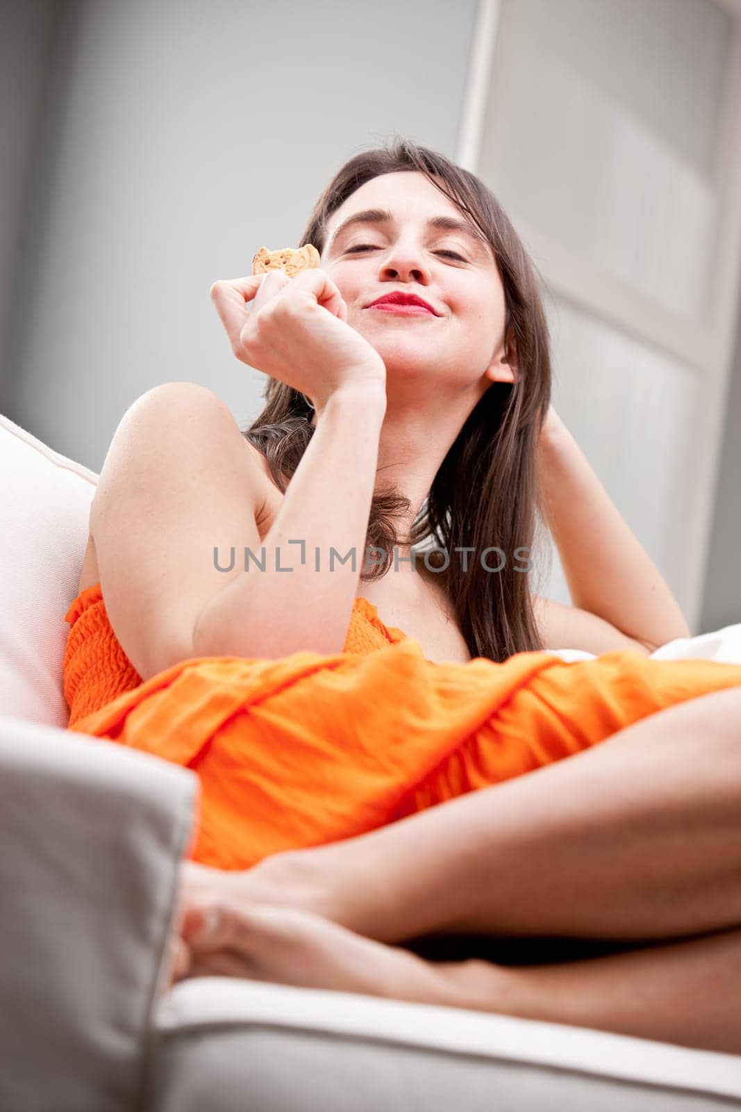 pretty young woman tasting a delicous biscuit in her sofa in complete relax