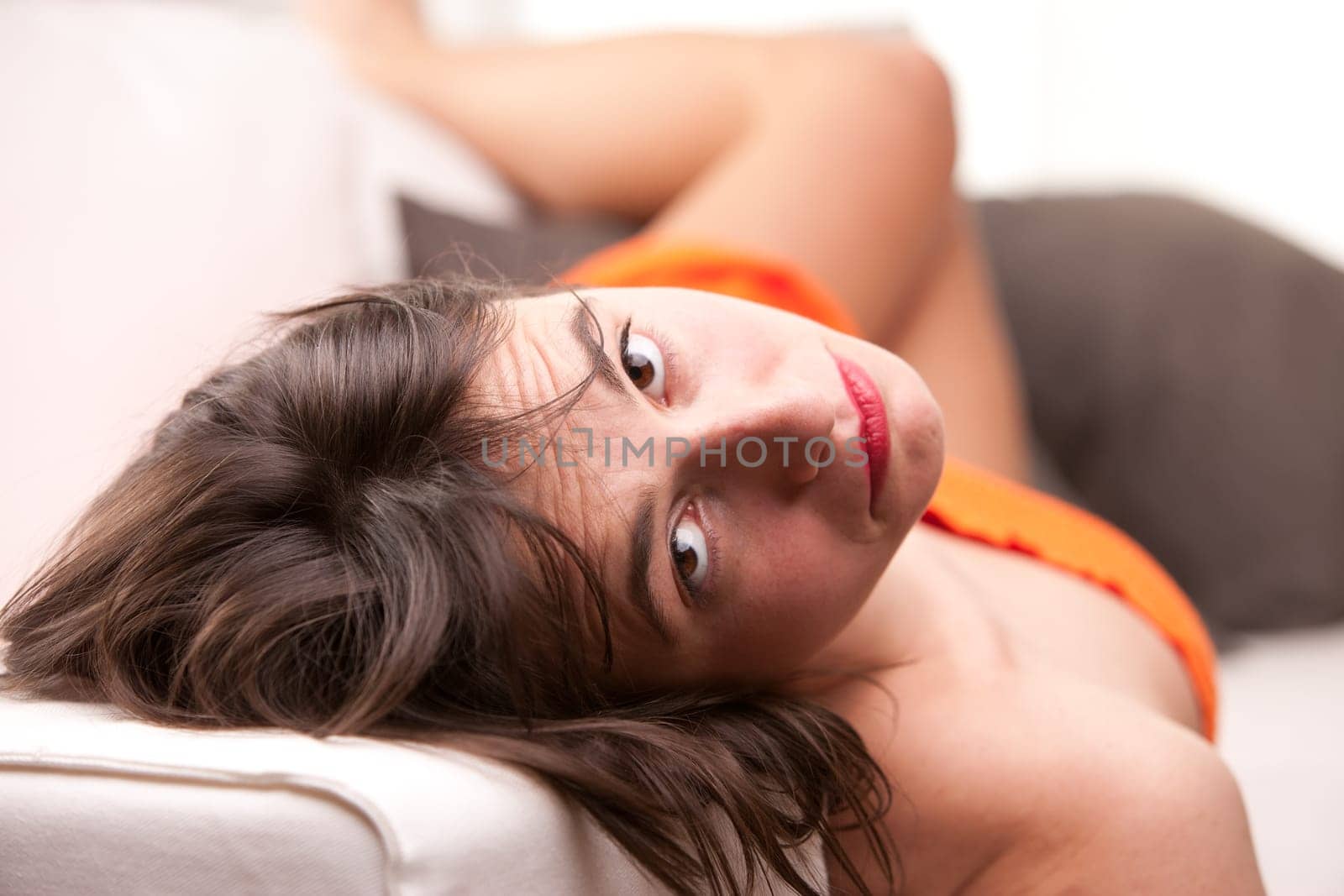 a sexy girl intense gaze while lying on her sofa