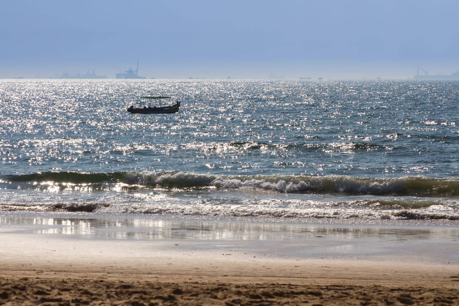 Boats at Arabian sea. Cargo ships on the background. View from beach in Goa, India