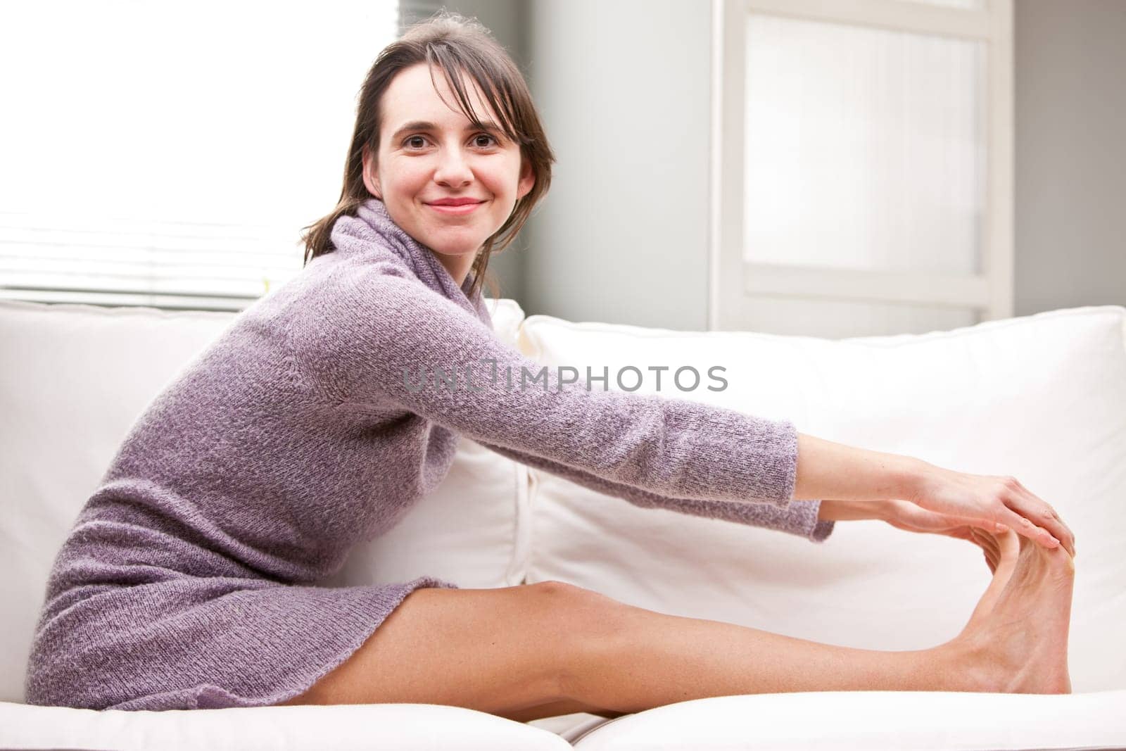 pretty girl doing stretching exercises on her sofa