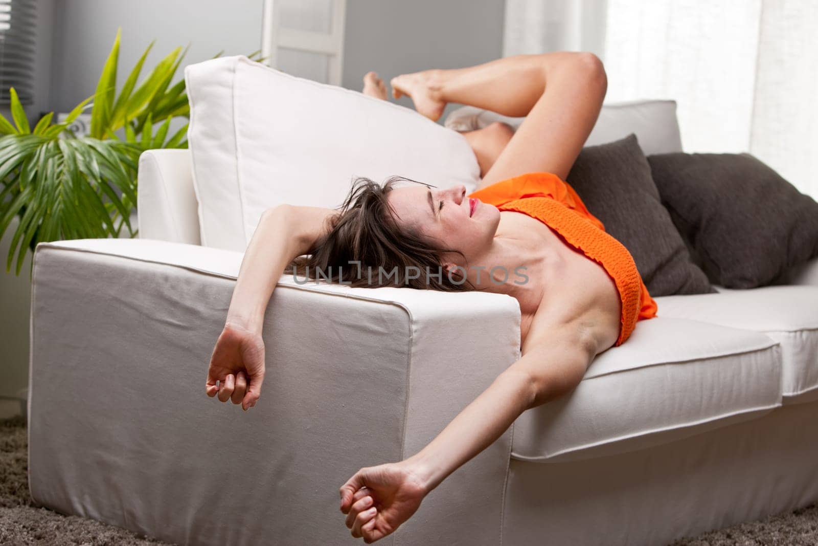 long legs girl yawning and stretching on her sofa while she wakes up