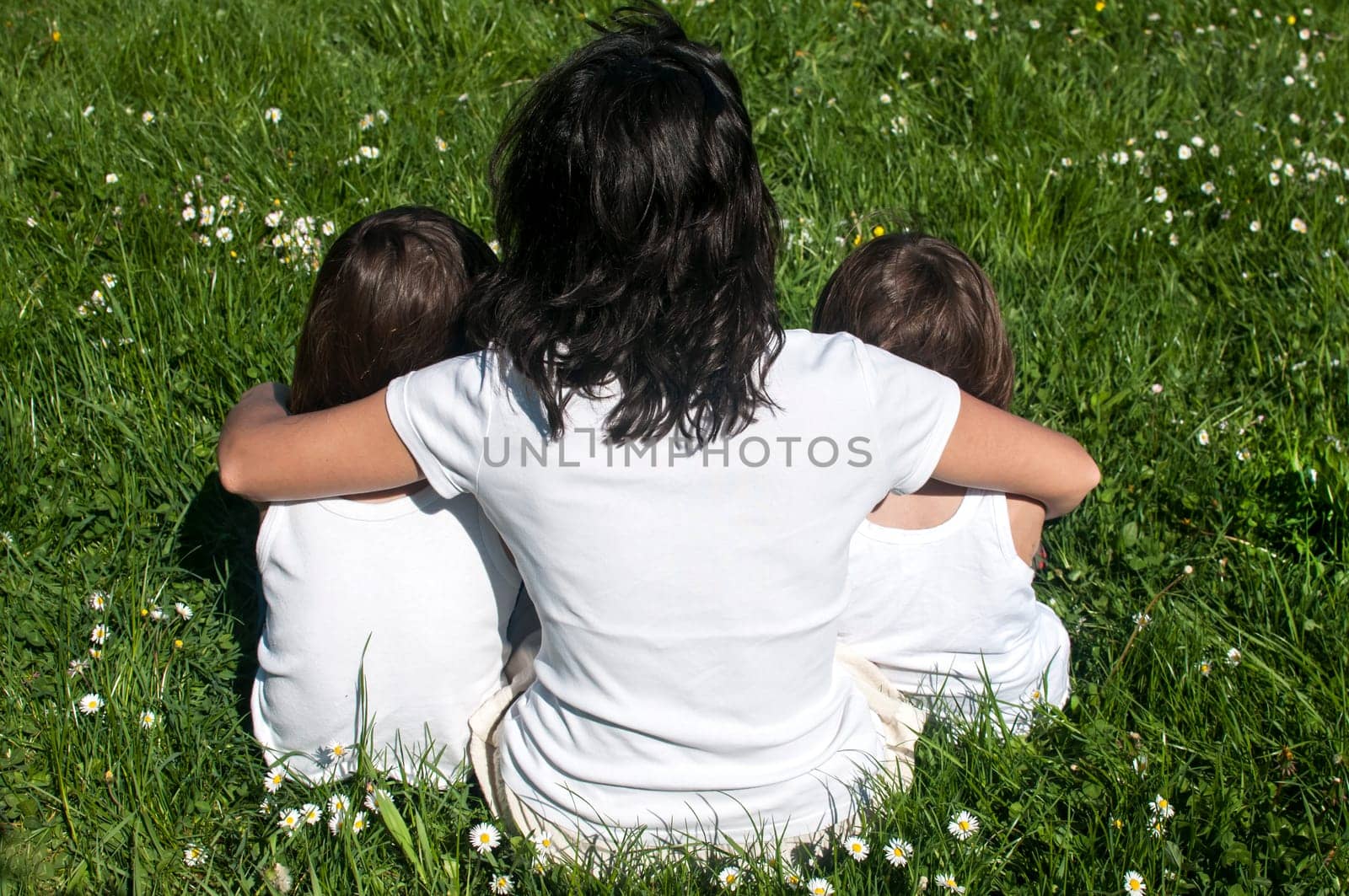 Mother with two children sitting back on spring meadow