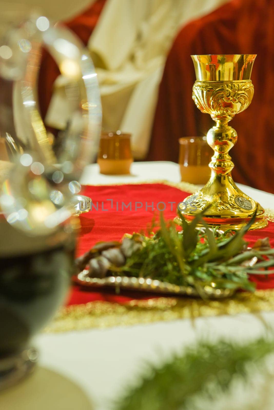 Gold sacred chalice with holy bread and wine over red tablecloth