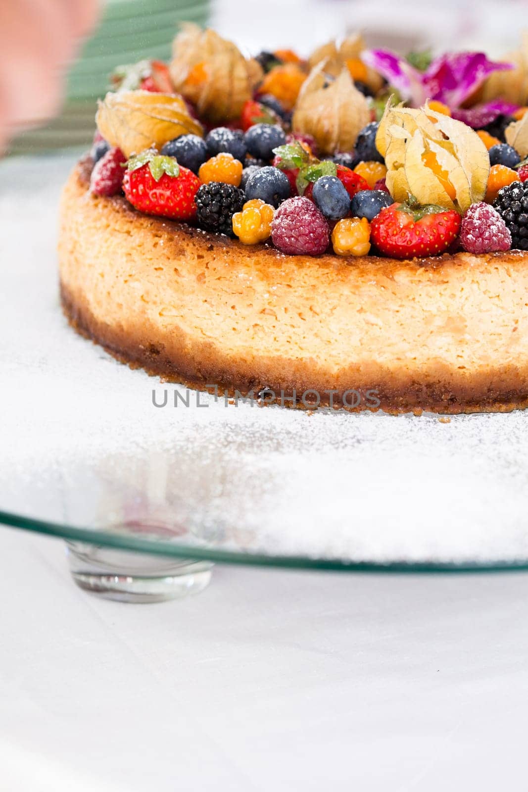 Closeup of delicious sponge cake topped with fresh berries on glass serving tray