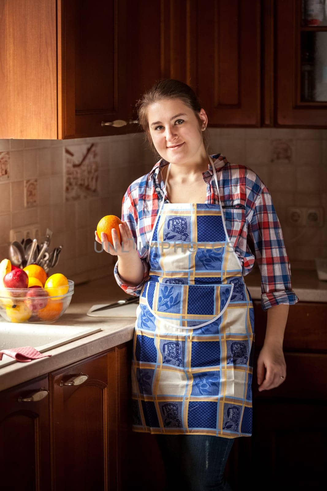 Portrait of happy housewife eating cucumbers from salad