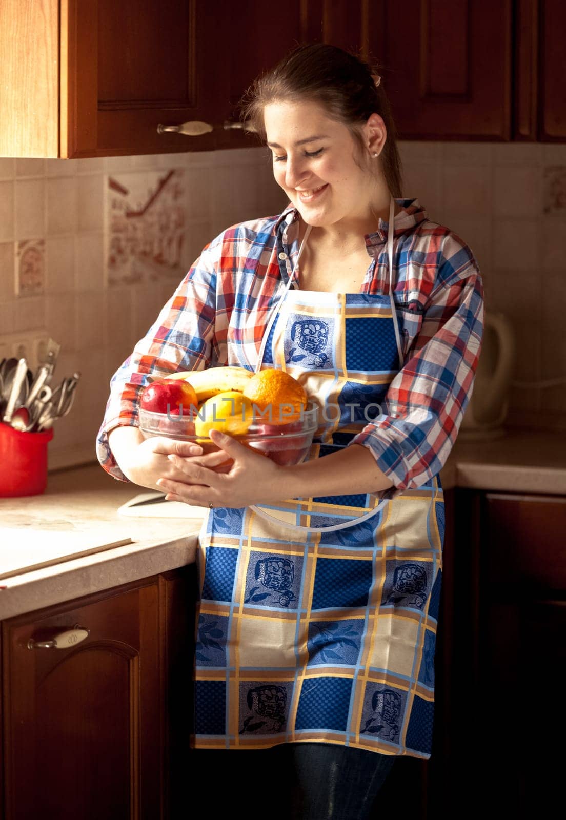 Portrait of happy housewife eating cucumbers from salad