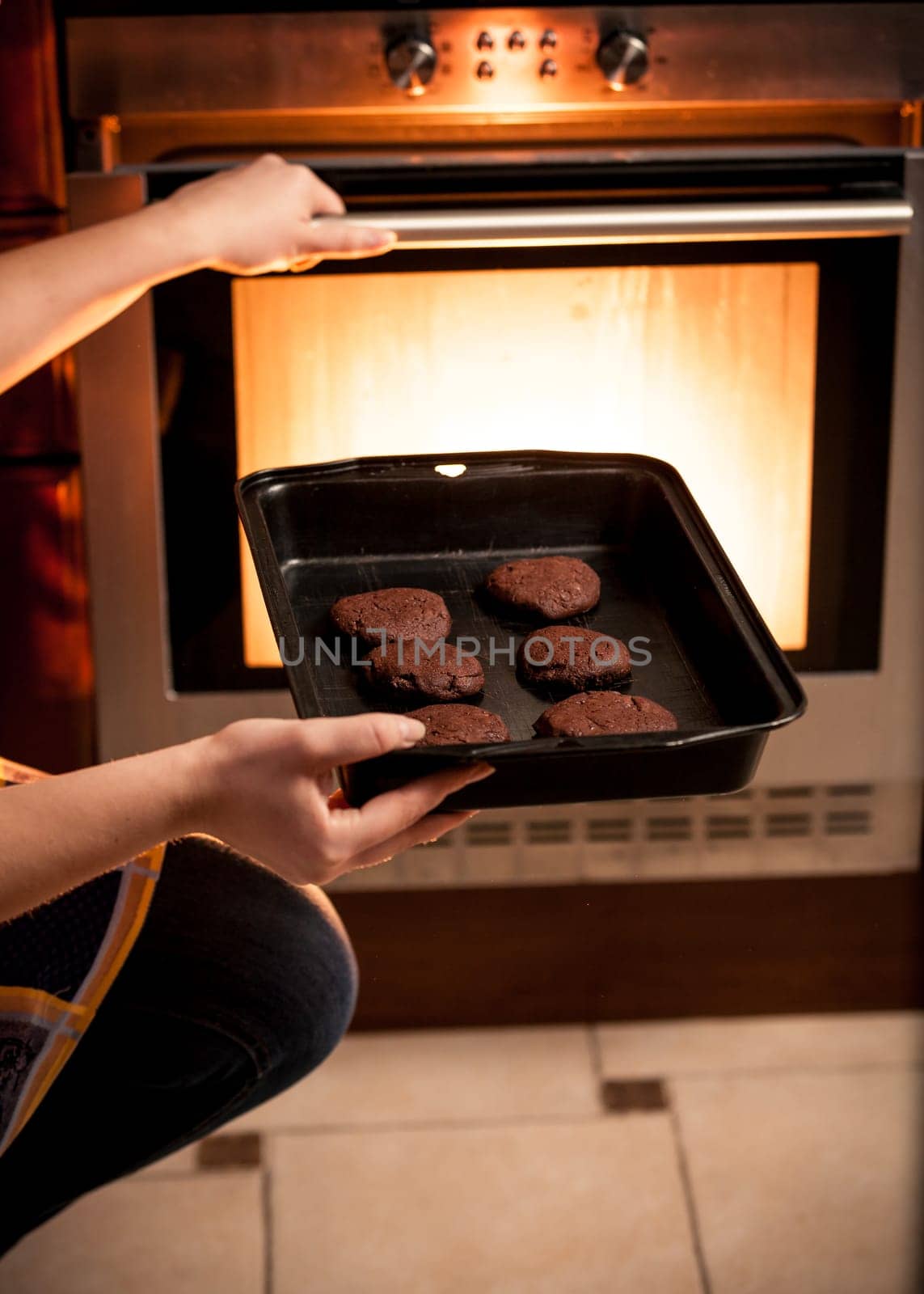 Closeup photo of housewife putting pan with cookies in oven