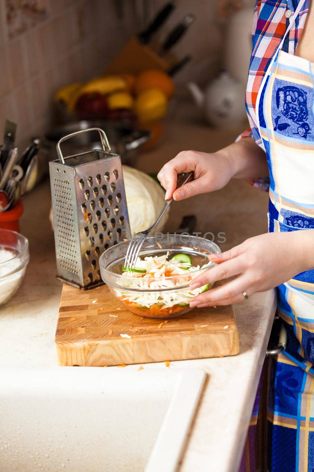 Closeup photo of woman eating salad with fork on kitchen