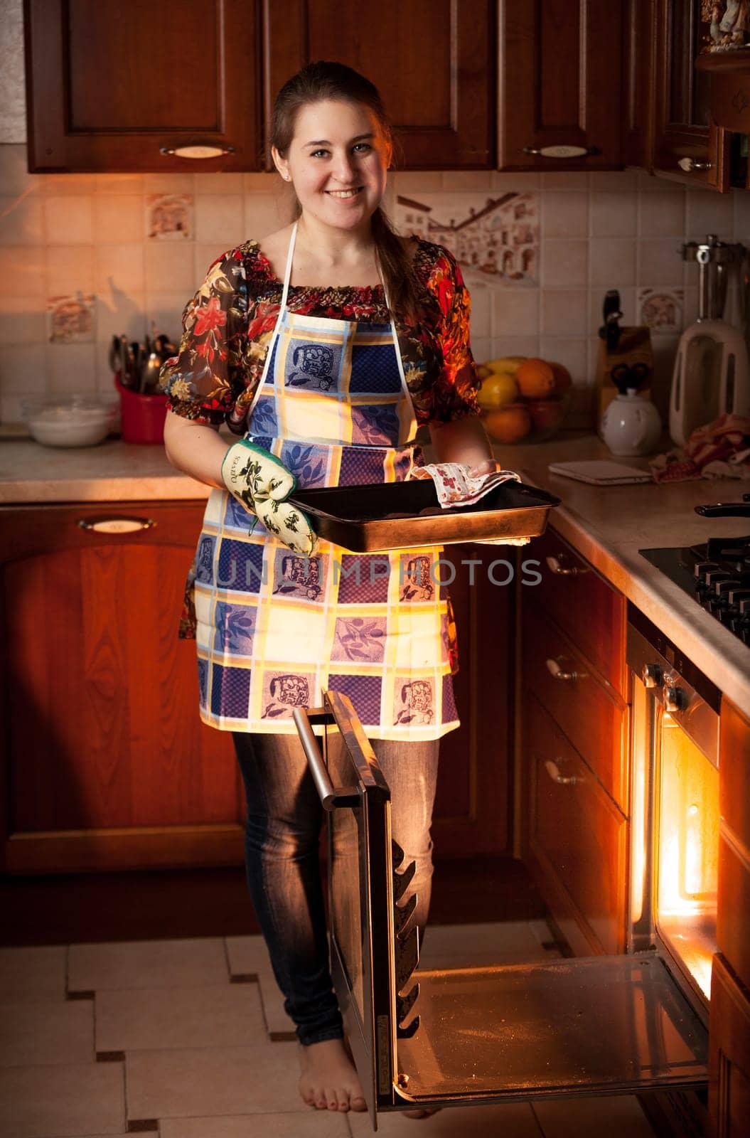 Beautiful housewife holding form with chocolate cookies near oven
