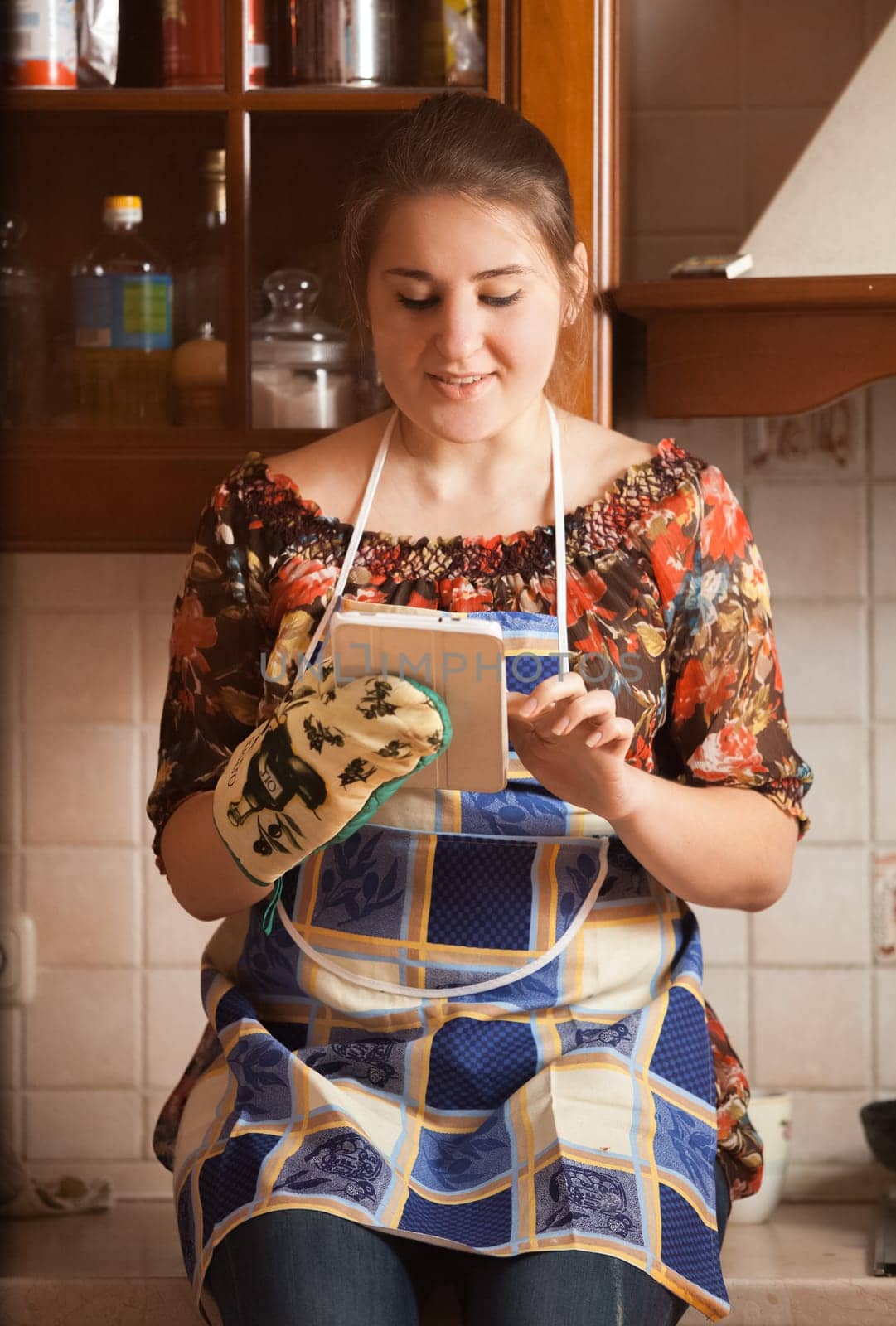Closeup portrait of young housewife using tablet while cooking