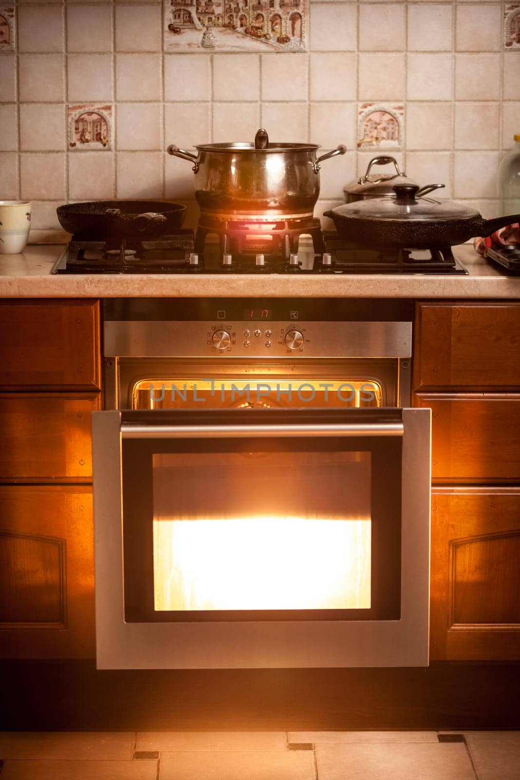 Photo of hot oven and pan boiling on stove at kitchen